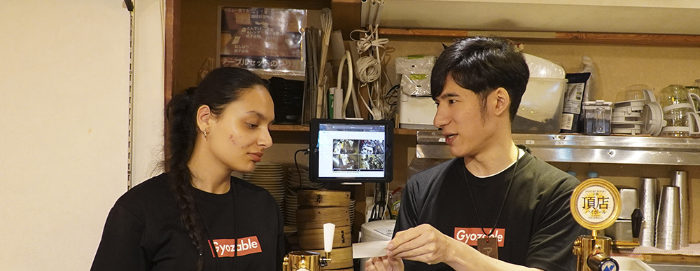 International staff member practicing customer-service Japanese with a colleague at Gyoupao